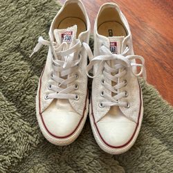 These are classic white Converse Chuck Taylor All Star low-top sneakers featuring red piping around the sole