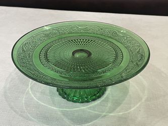 Green pressed glass footed cake stand with embossed Renaissance pattern. 7.75”