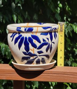 Ceramic planter features a glazed blue leaf pattern against a textured white background