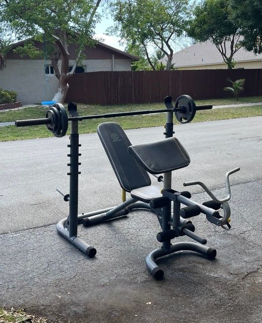 GOLDS GYM ADJUSTABLE BENCH / BAR & HOLDER /  & 130 LBS  OF PLATES : (With Arm & Leg Attachment) + BARBELL BAR & 130 LBS. OF GOLDS GYM OLYMPIC PLATES