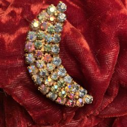 vintage crescent-shaped brooch or pin, featuring aurora borealis rhinestones in various colors set in a gold-tone metal base.