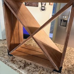 This is a small, freestanding wooden wine rack designed for a countertop or table