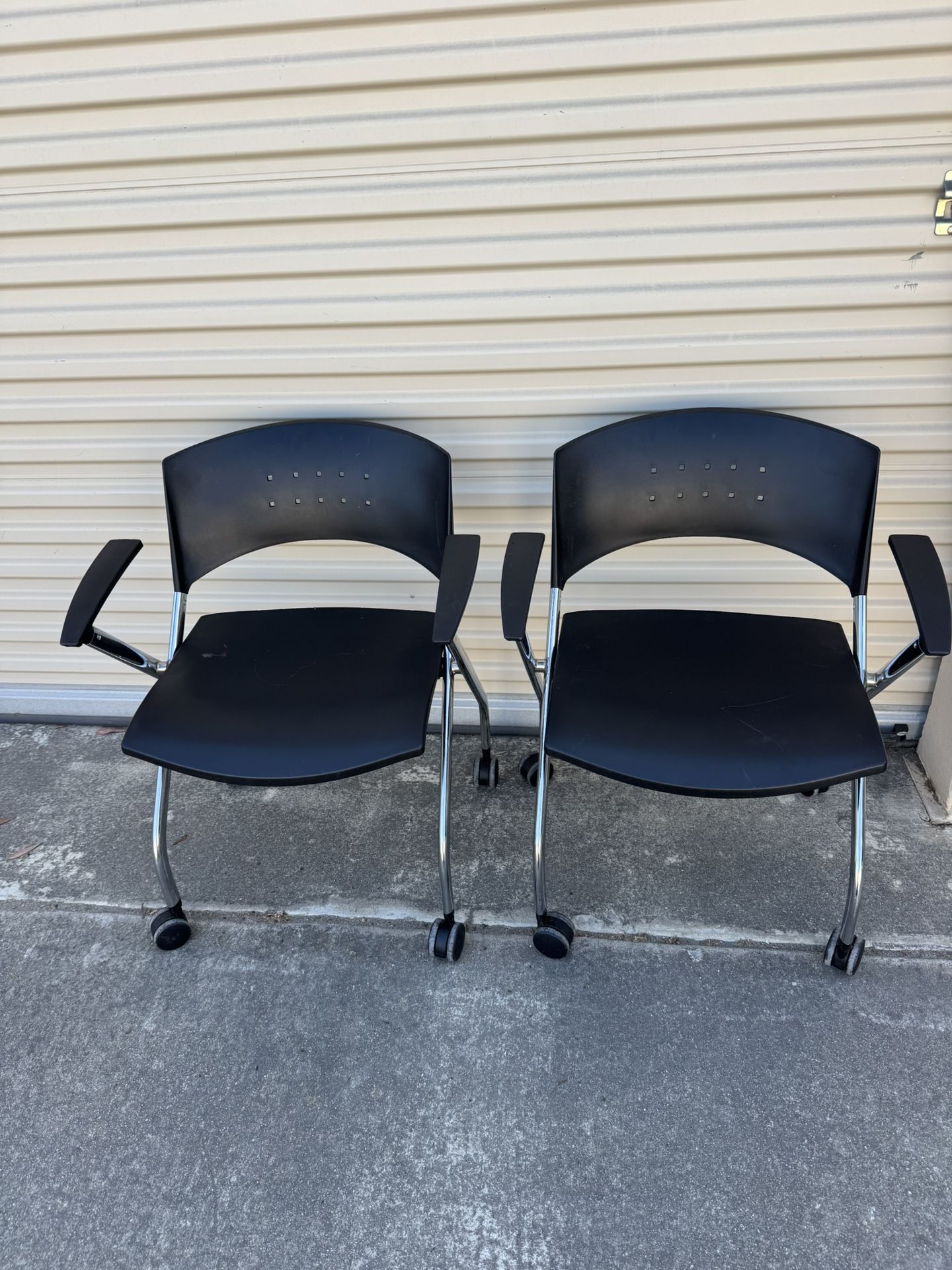 2 Nesting chair with casters. Black plastic back and seat with chrome frame.