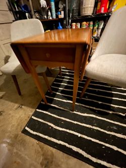 Versatile West Elm dining set. You have a wooden drop leaf table and 2 upholstered chairs. Chairs are light gray fabric with wooden legs. Table is a n