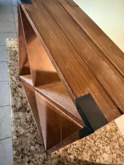 This is a small, freestanding wooden wine rack designed for a countertop or table