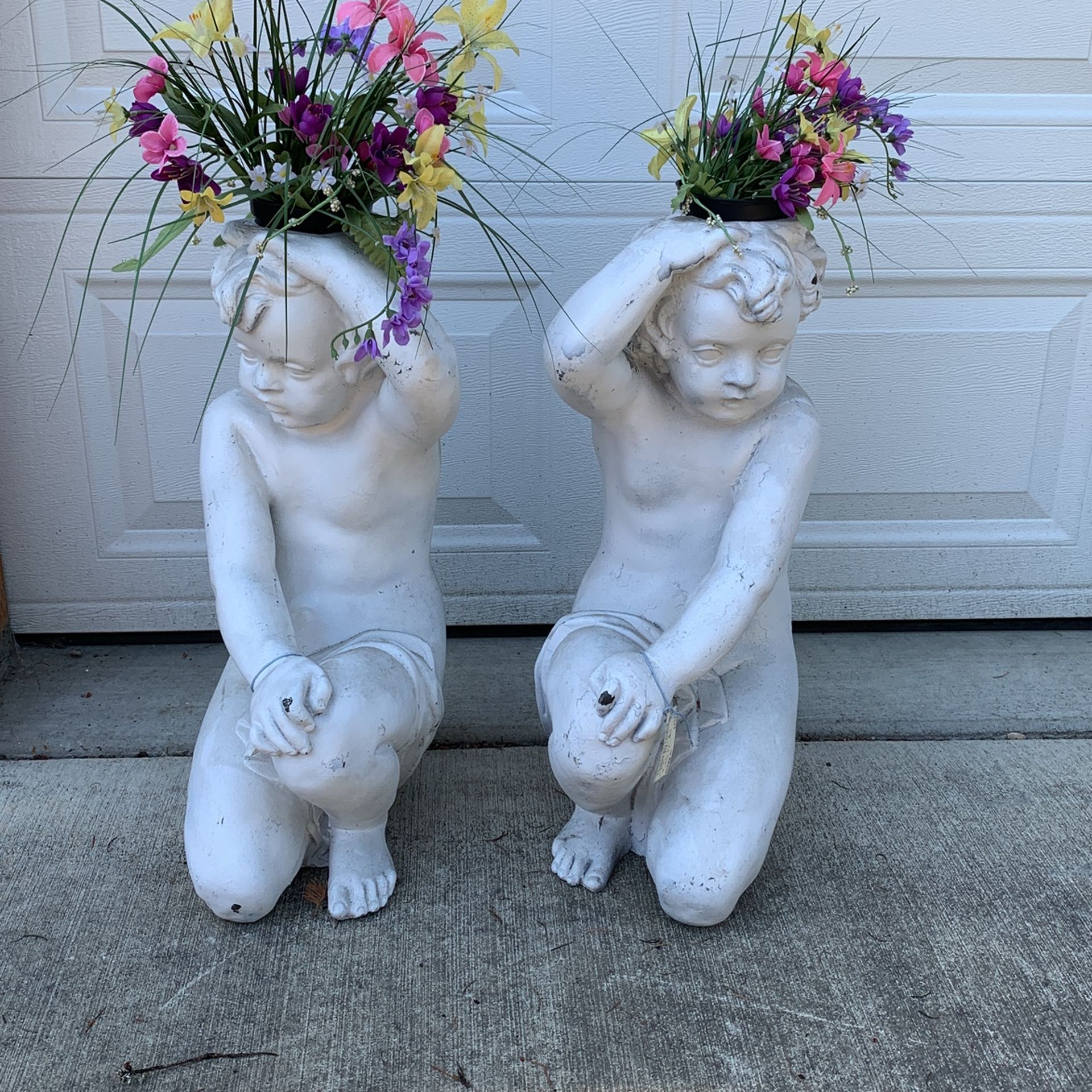 Two fiberglass cherubs plant stands