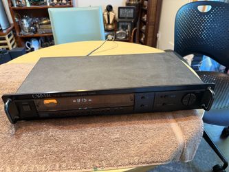 Vintage Carver TX-12 synthesized stereo tuner is black with a digital display and analog signal meter. This unit has a rack-mount design with front ha