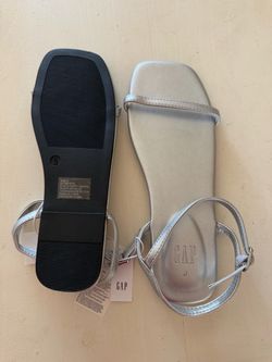 These are Gap brand vegan-leather strappy sandals in a silver metallic finish.  * They feature a modern square toe silhouette and a slim toe strap. * 