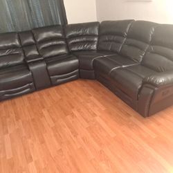 Black leather power reclining sectional sofa with a console and cup holders. 