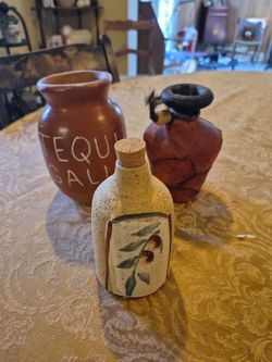 Three unique items a ceramic tequila jar a olive oil bottle and a clay pottery
