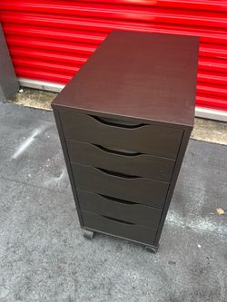 IKEA ALEX drawer unit on casters featuring a dark black-brown finish and rolling wheels.