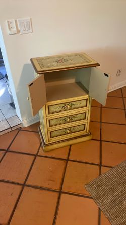 small, hand-painted accent cabinet or chest of drawers, often referred to as a jewelry armoire or lingerie chest