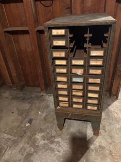 Vintage industrial steel small-parts cabinet with multi-drawer layout, open upper shelving, and authentic patina.