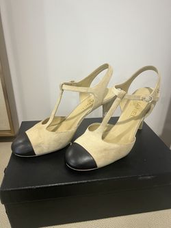 Chic CHANEL heels with a classic T-strap design. Beige body with black toe cap. Ideal for elegant occasions.