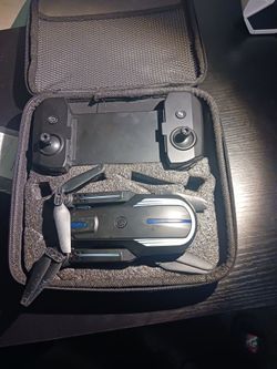 A black drone still works missing two of its batteries and it comes with a controller that extends to fit your phone
