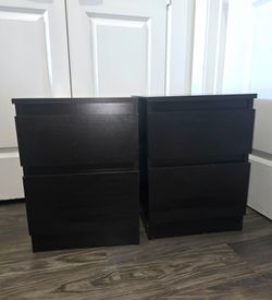 A pair of black Ikea nightstands