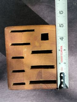 Solid wood knife block has a natural light brown finish. This storage block includes nine slots for various knife sizes and one square slot for kitche