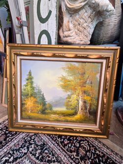 A classic-style oil painting depicting an autumnal woodland landscape with trees in shades of gold and green, set in an ornate gold wooden frame.