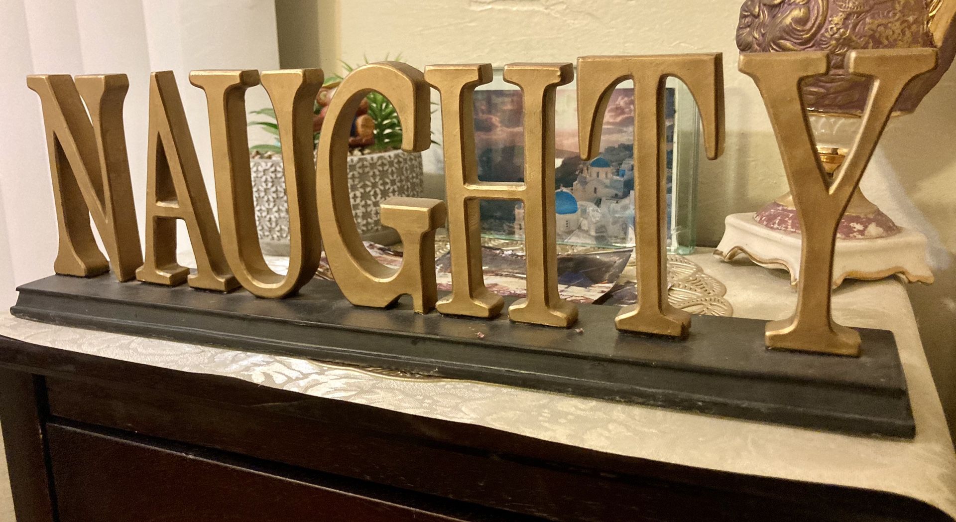 Novelty gold-painted wooden “Naughty” sign