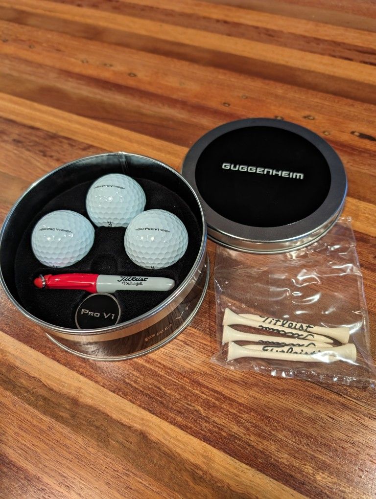 Titleist Collectors Tin Pro V1 Set - Guggenheim New. Comes with 5 tees, ball marker, mini sharpie, and 3 Pro V1s with Guggenheim logo.