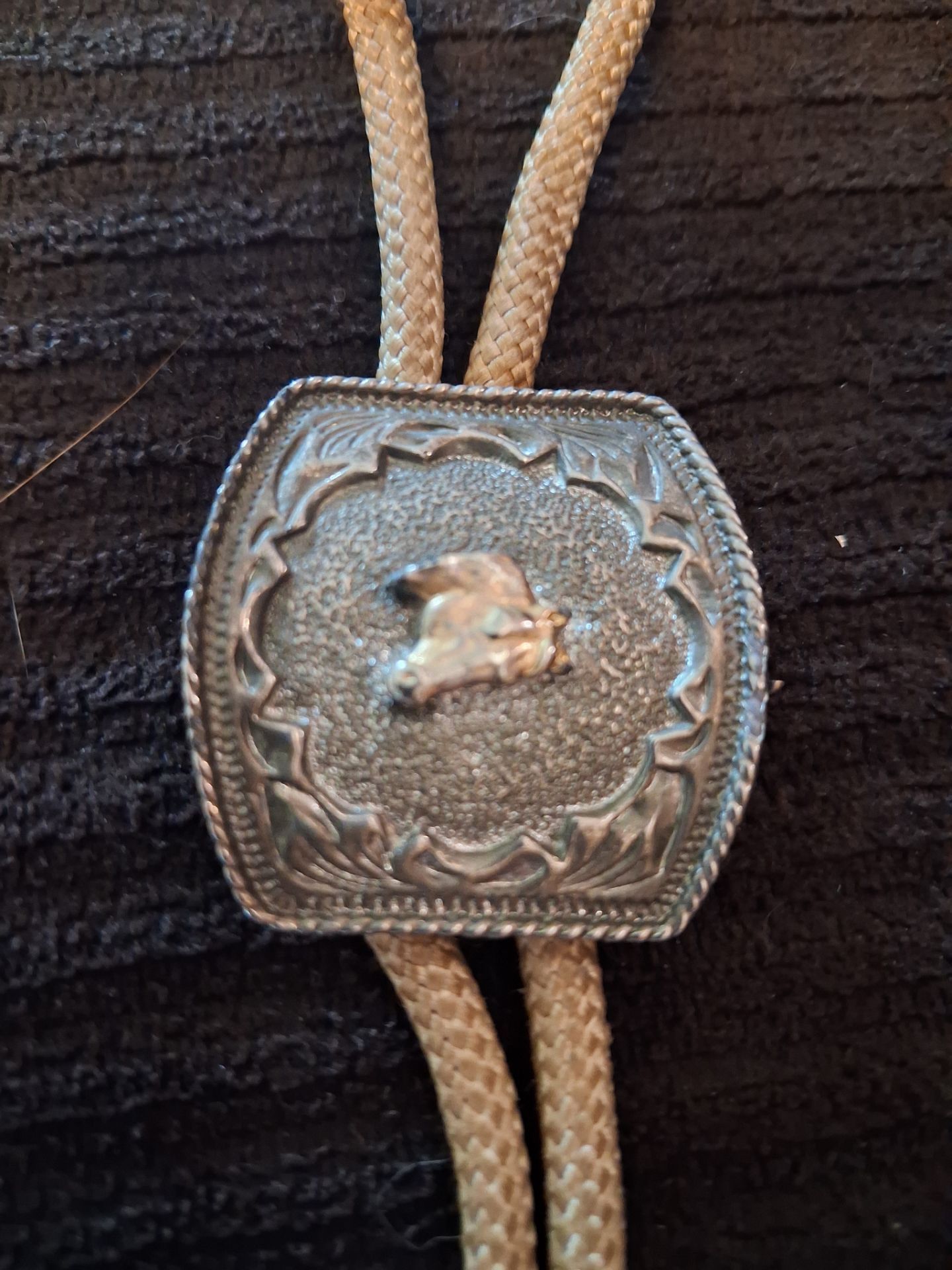 vintage silver-toned square bolo tie featuring a textured background and a raised horse figure in the center.