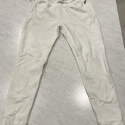 Comfortable white jogger pants with drawstring and zippered pockets.