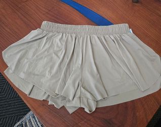 Light beige women's athletic skort shorts with a soft, flowy overlay and built-in shorts for coverage. Wide Elastic waistband for a comfortable, secur