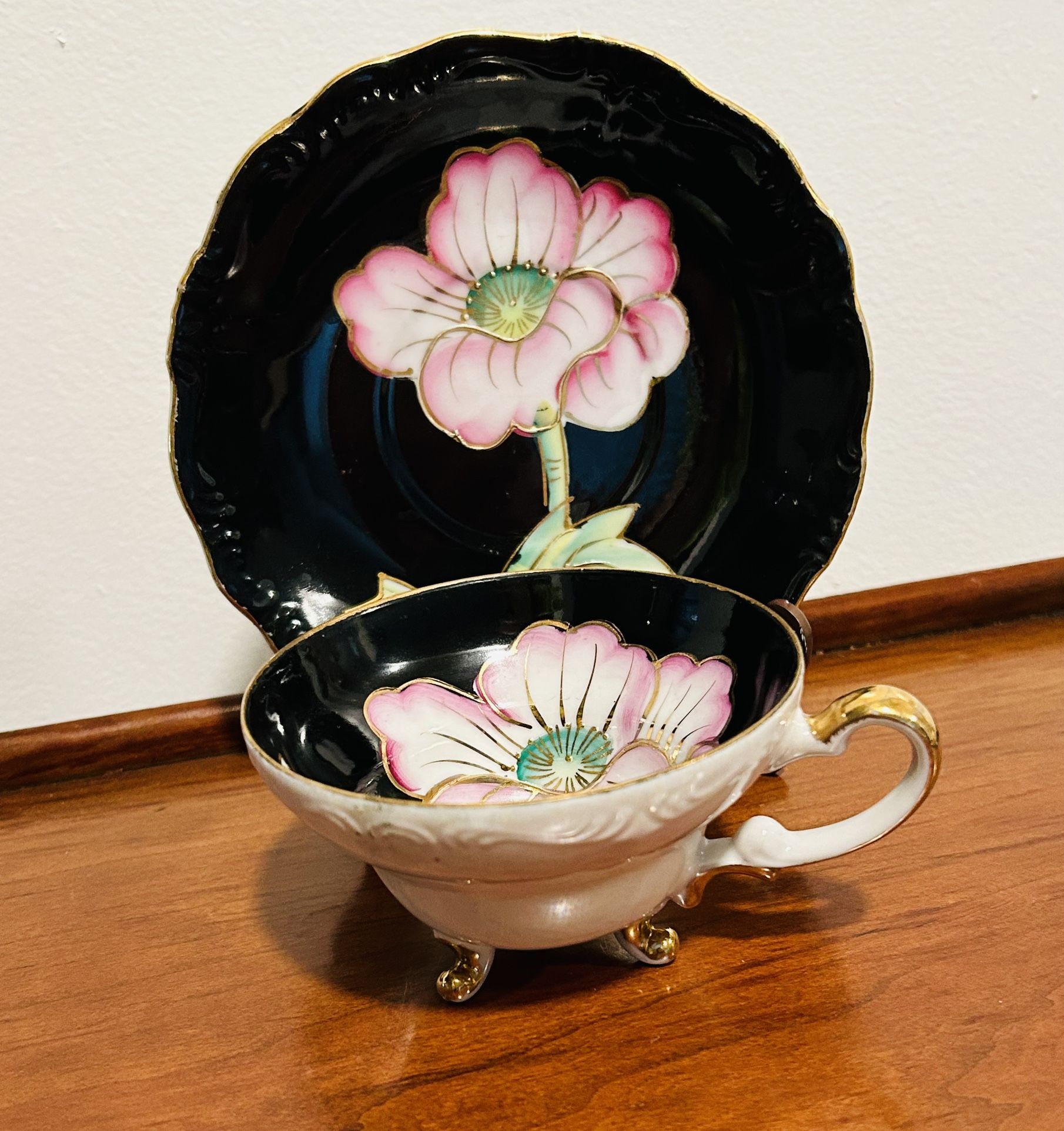 Vintage glossy white and black 3 footed china tea cup and saucer set with pink flower and gold accents