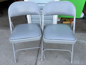 two gray metal folding chairs with padded vinyl seats and backrests