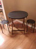 Small round wooden table and two plastic top stools.