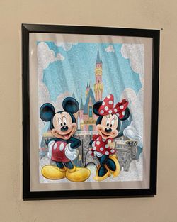 Disney Mickey Mouse and Minnie Mouse art piece on black frame infron of castle