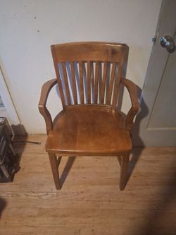 +2                    The image shows a vintage solid wood banker's or courtroom armchair with vertical slats and a warm honey finish