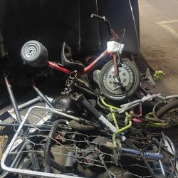 Pile of scooters, bikes, parts, hoods, and trash.