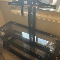 A Z-Line Designs entertainment center with a built-in TV mount and black tempered glass shelves