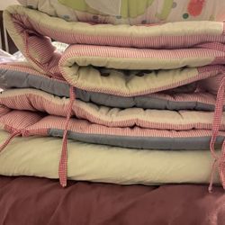 a small quilt, a baby crib bumper, and a sleep sack