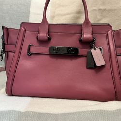 Chic Coach satchel in vibrant fuchsia leather. Features elegant handles and sleek hardware.