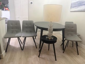 Black dining table with 4 grey chairs, kids table and side table and lamp