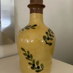 Yellow ceramic bottle with leaf design and cork stopper.