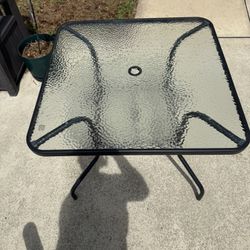 Outdoor patio table in excellent condition. Tempered glass top with sturdy metal frame. Very clean and well taken care of. Features a center umbrella 