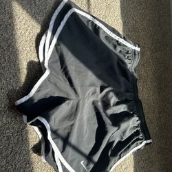 Four pairs of nike shorts two black and two purple.
