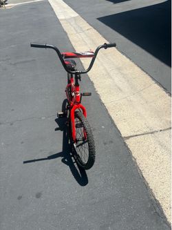 A Red Huffy Rock It kids' bike features a BMX-style design with a protective handlebar pad