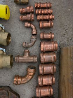 Plumbing valves, copper couplings, a ridgid battery and a 1/2 inch claw.