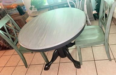 Round gray farmhouse table with sage green chairs