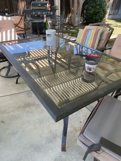 Patio glass table with six chairs and two small benches