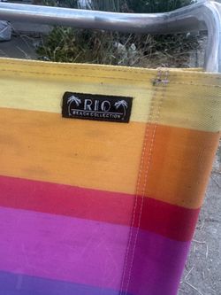 Rio Brands rainbow striped folding beach chair with wooden arms.