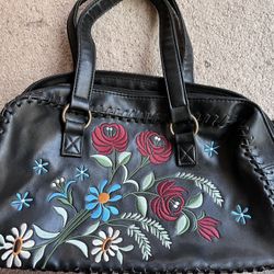Black handbag with colorful floral embroidery.