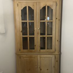 This American country style solid pine corner cabinet features a glass-front display hutch on top and closed storage panels below.