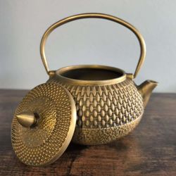 An antique teapot with a woven handle, a decorative work of art.