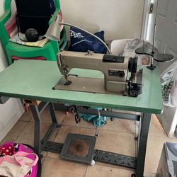 Heavy-duty industrial sewing machine is a Consew model 230R-1. It has a large green work table with a built-in ruler along the edge. Unit includes a m