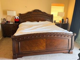 Ashley North Shore sleigh bed featuring ornate dark wood carvings with 2 night stands